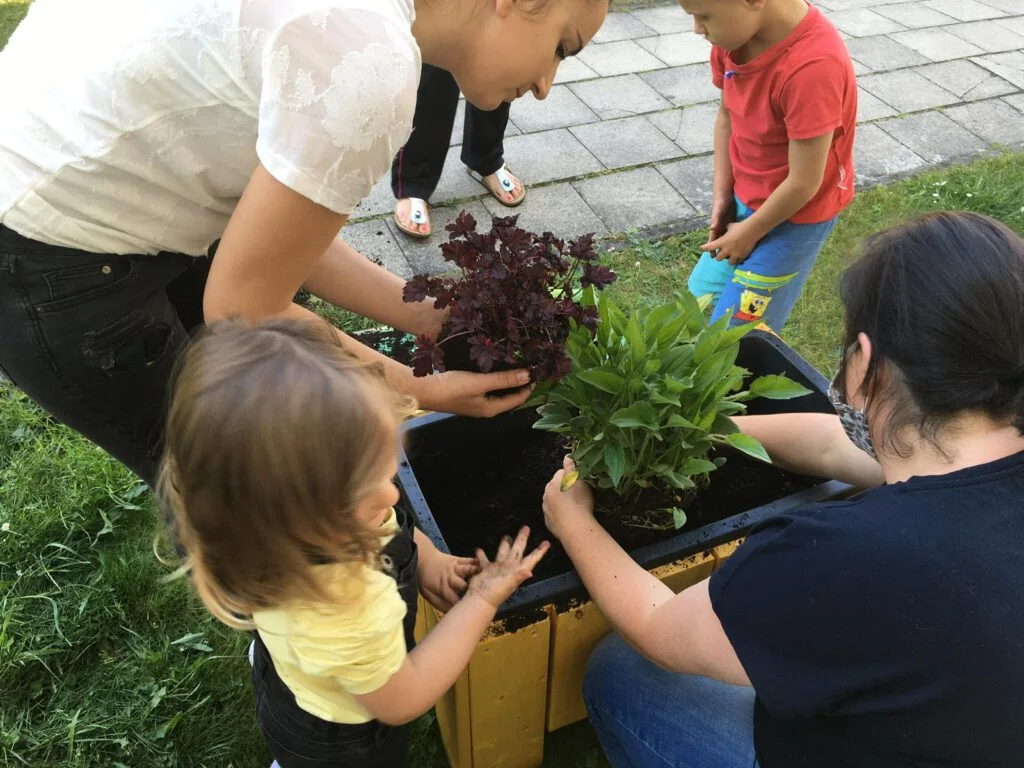 Kinder und Erwachsene bepflanzen ein Hochbeet im Wohngebiet