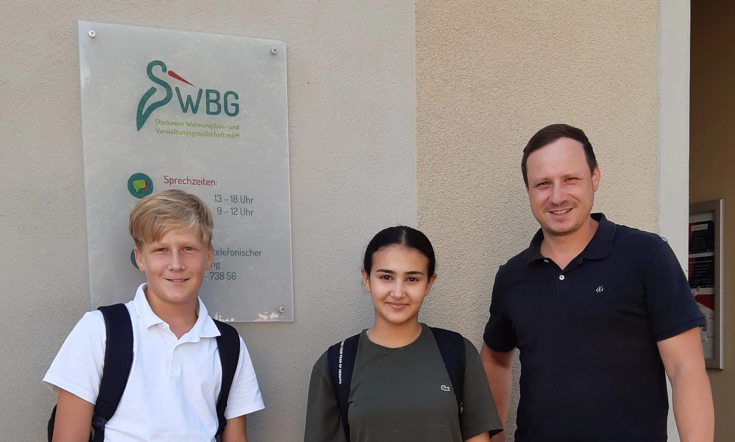 Zwei Praktikantinnen und Praktikanten der Europaschule mit einem Mitarbeiter vor dem Büro der Storkower WBG