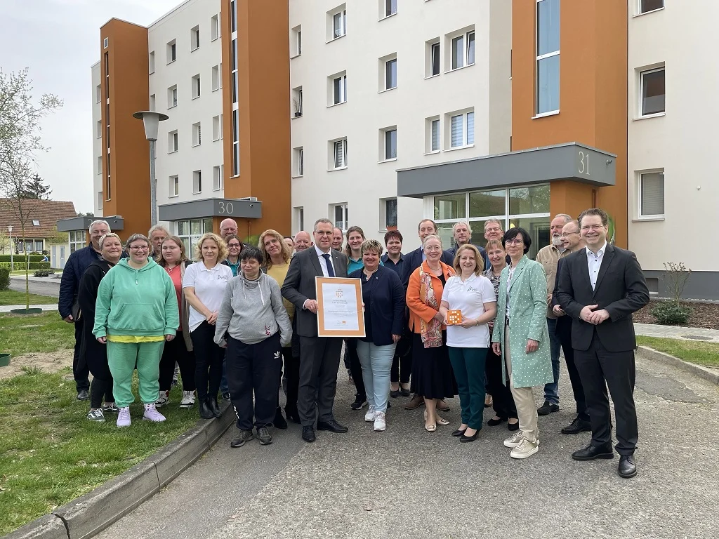 Übergabe des Siegels „gewohnt gut“ an die Storkower WBG mit dem Team vor den Häusern 30/31
